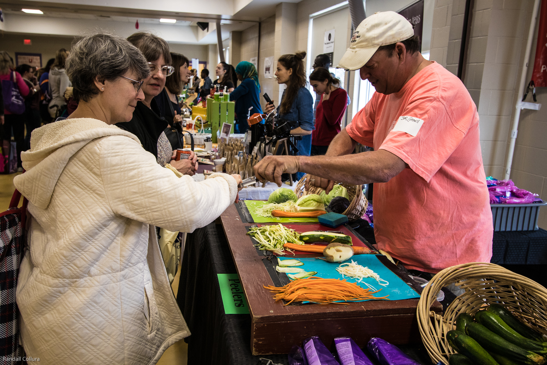 An exhibitor hands sliced veggies to a woman