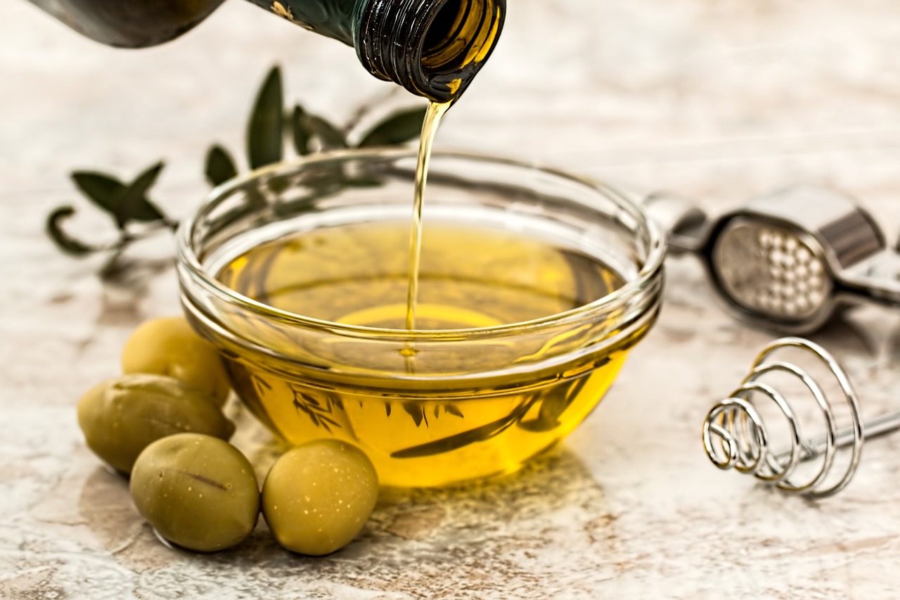 olive oil pouring out of a bottle into a bowl
