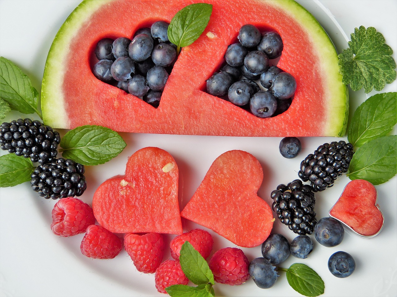 slice of watermelon with heart-shaped cutouts filled with blueberries