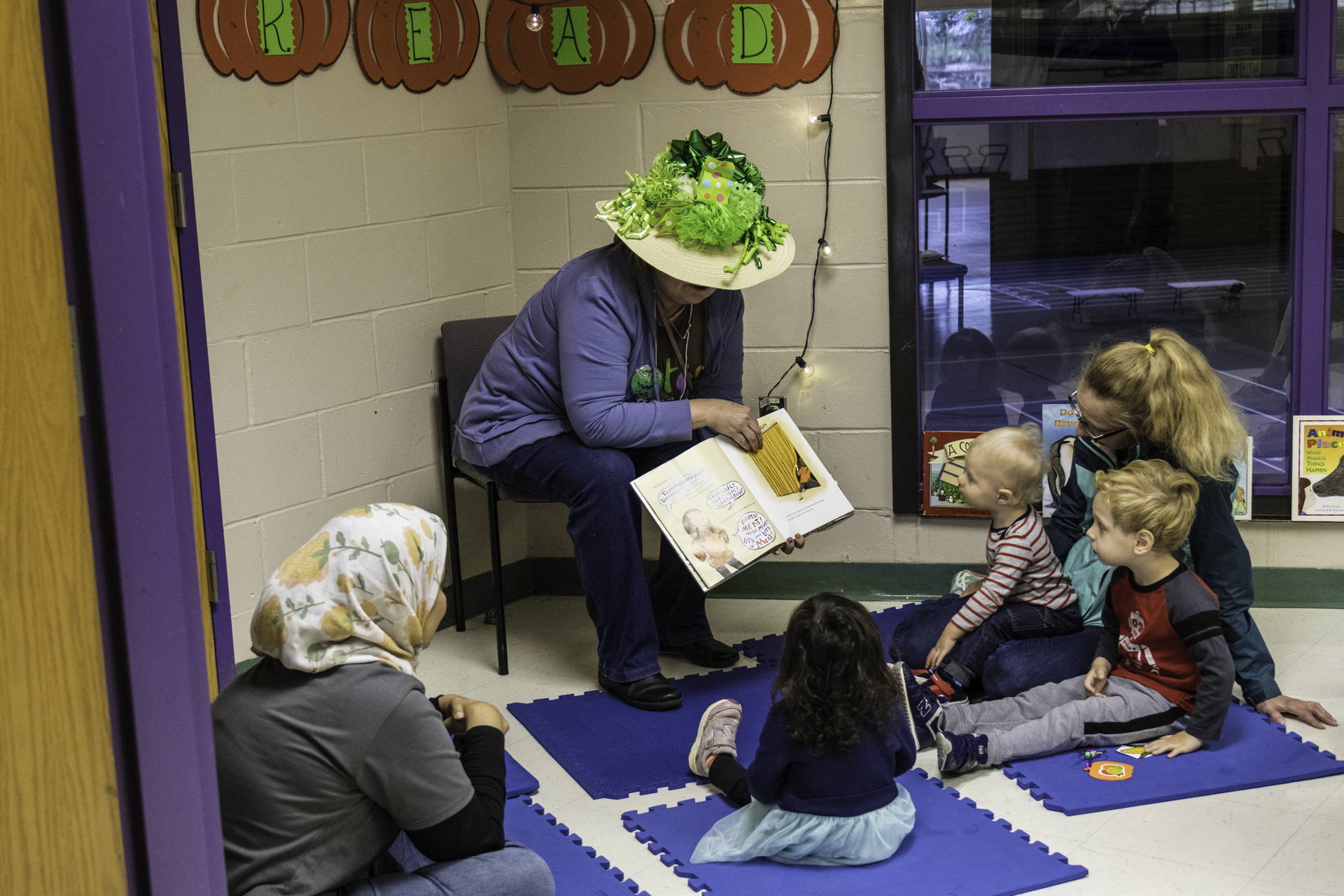 a volunteer reads a book to young children in the kids activity room