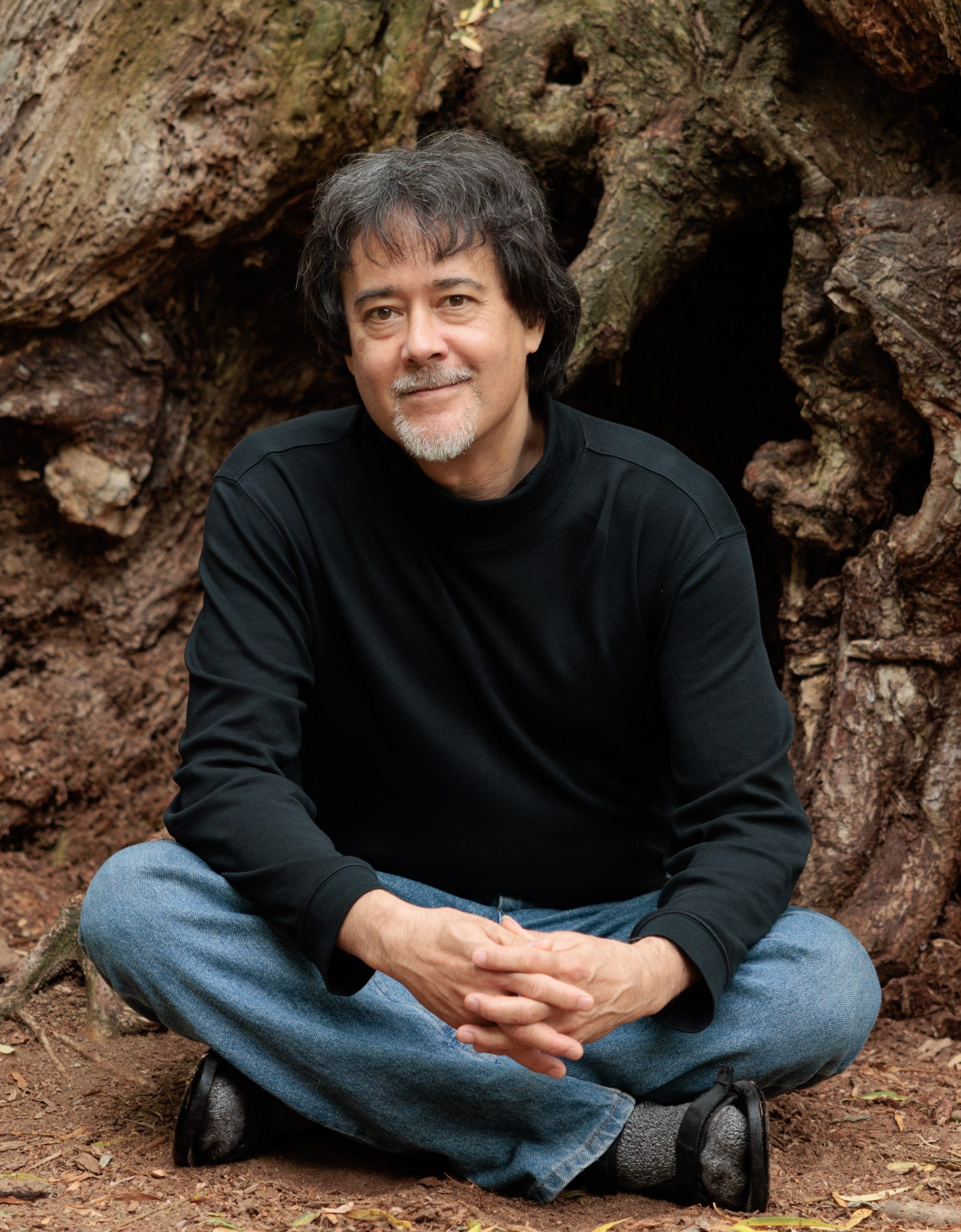 John Sanbonmatsu sitting at the roots of a large tree
