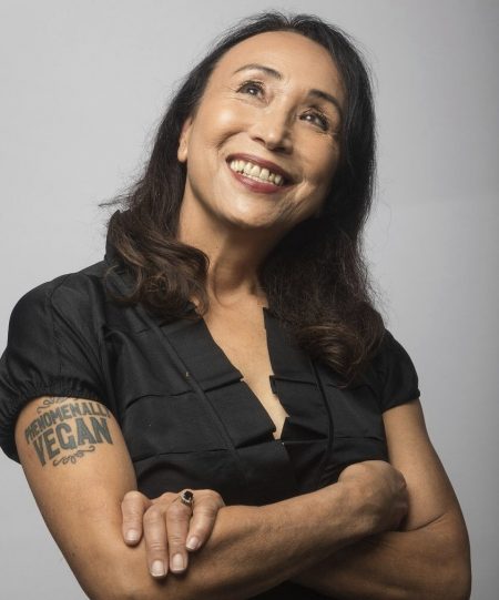 Miyoko Schinner posing with a tattoo on her arm that says Phenomenal Vegan