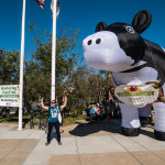 woman poses in front of giant inflatable cow at the entrance to Boston Veg Food Fest 2017