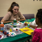 volunteer and a child at the kid's table with paints